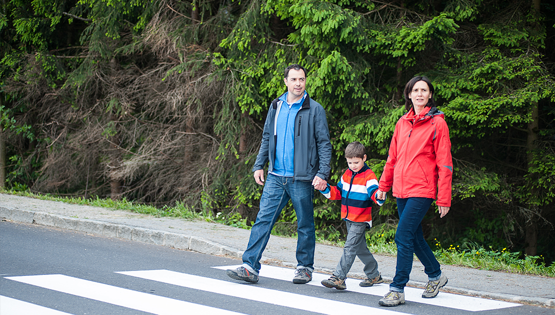 Two adults and a child walking across a crosswalk