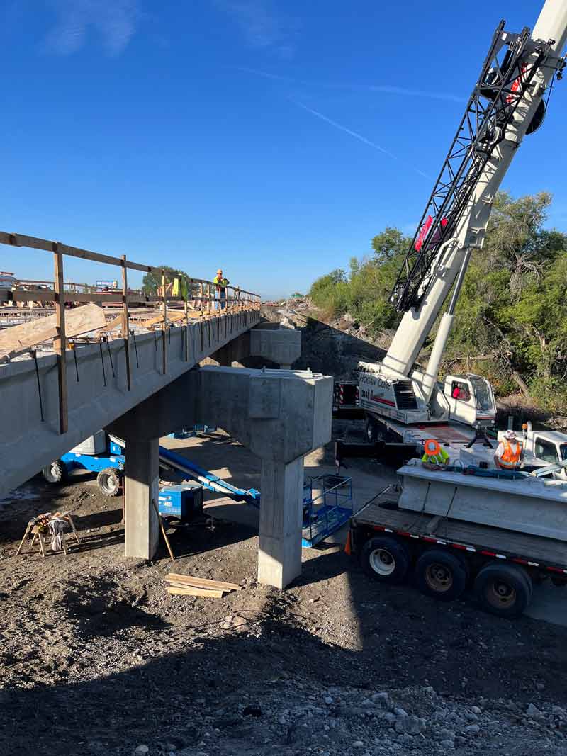 A crane is used to install a new girder on the westbound bridge structure above 56th Street West. Girders are horizontal beams that support the bridge deck.