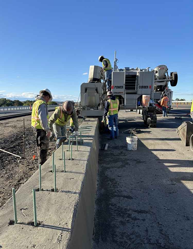 Crews building concrete road barriers.