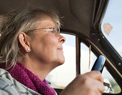 older woman struggling to look over the steering wheel